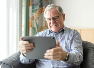 Frequent online socializing leads to better mental health in seniors Senior man sitting at home using digital tablet for video calling. Mature man having online consultation with doctor.