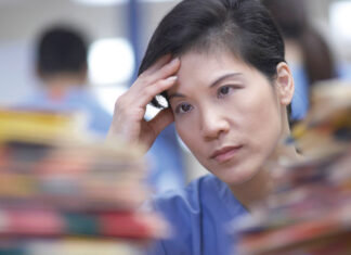 Senior living and care workforce faces mental, physical health challenges: report worker with hand to head