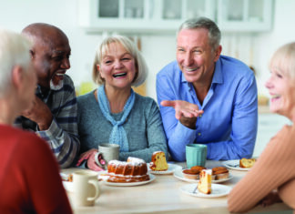 Tips for Seniors to Safeguard Their Mental Health Multiracial group of happy senior people sitting around table drinking tea with cake and having conversation, smiling and laughing, having home party or enjoying time at nursing home