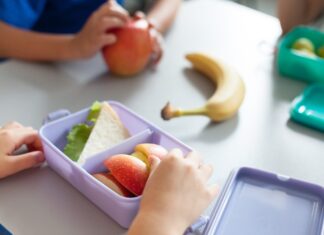 A new study shows ultra-processed food makes up 59% of children’s food School kids eating healthy food from packed lunch boxes. Children at table in cafeteria. Pupils have vegetarian breakfast in canteen. Back to school concept. Lifestyle moment in elementary college