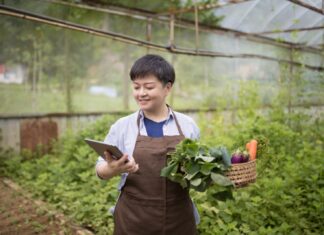 Is eco-friendly the same as health food? Chinese woman using digital tablet examining her growth farm.