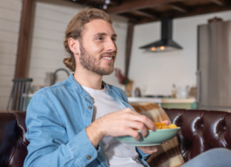 Do artificial colors in food cause cancer? Man sitting on couch eating from bowl of chips