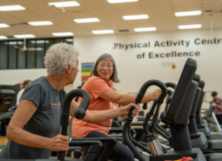 Community exercise programs help seniors fight age-related decline Two smiling older adults working out in an indoor gym with the worlds Physical Activity Centre of Excellence on the wall behind them.